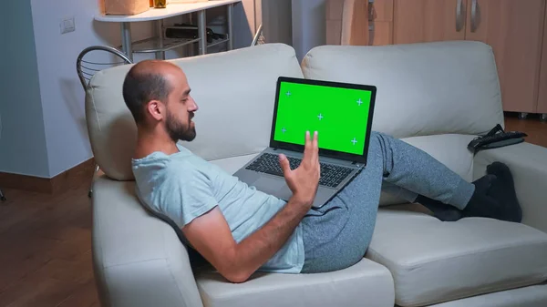Tired man sitting on sofa while browsing marketing information using laptop computer — Stock Photo, Image