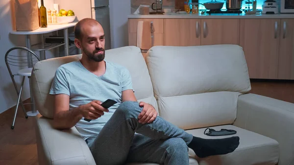 Hombre cansado sentado frente a la televisión viendo series de películas de entretenimiento —  Fotos de Stock