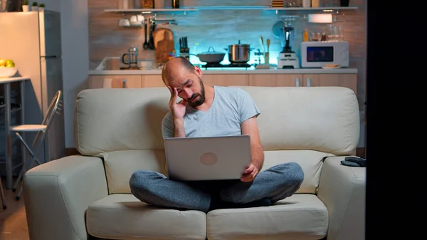 Homme fatigué en pyjama naviguant sur Internet informations sur le mode de vie — Photo