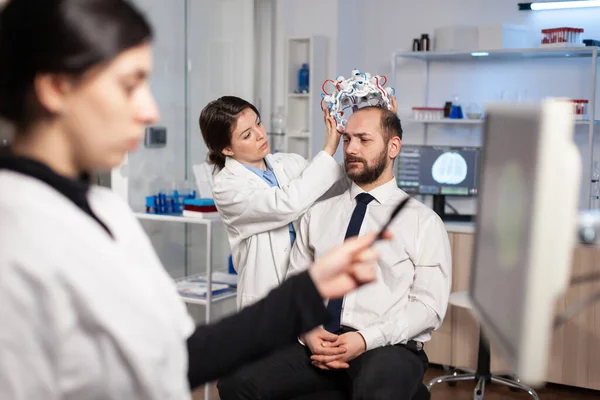 Investigador de neurología ajustando auriculares cerebrales en el paciente durante el estudio — Foto de Stock