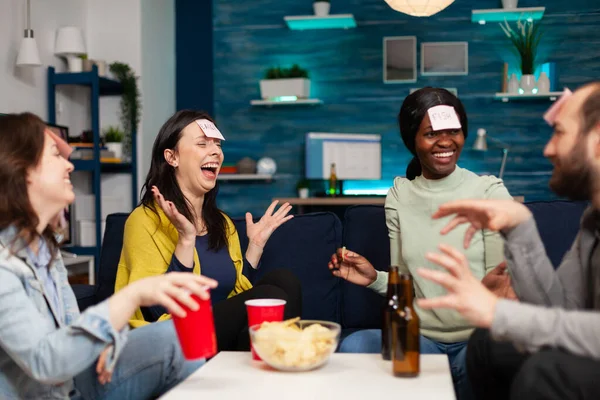 Amigos de corrida mista jogando jogo de tabuleiro usando notas pegajosas — Fotografia de Stock