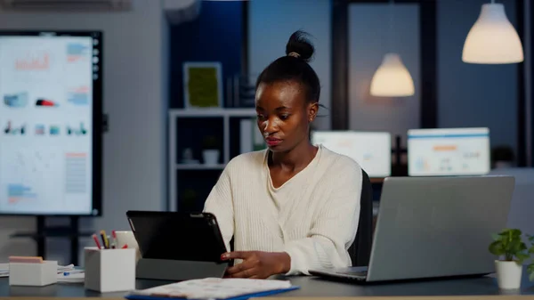 Africano gerente mulher usando laptop e tablet ao mesmo tempo trabalhando horas extras — Fotografia de Stock