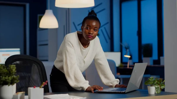 Manager black woman standing at desk searching on laptop and looking at camera — Stock Photo, Image