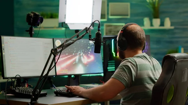 Concentrated streamer playing space shooter videogame using headset — Stock Photo, Image