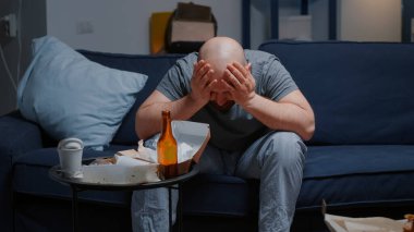 Depresyonda endişeli umutsuz bir adam. Kanepede oturuyor.