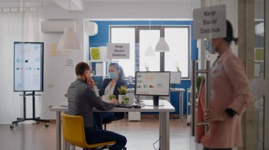 Koruyucu yüz maskeli bir iş adamı telefonda konuşuyor.