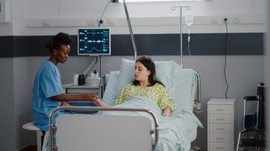 Afro-Amerikalı pratisyen hekim hasta kadını muayene ediyor. Nabız oksimetrelerini kontrol ediyor.