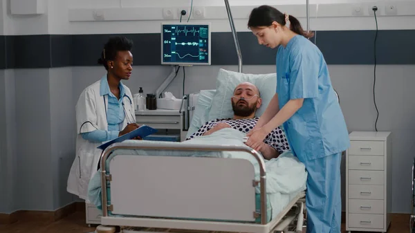 Kranker Mann sitzt mit Sauerstoffschlauch im Bett und erklärt Krankheitssymptom — Stockfoto