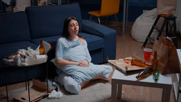 Stressed, depressed woman crying sitting in dirty room