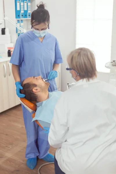 Zieke patiënt liggend op tandartsstoel met open mond voor medische procedure — Stockfoto