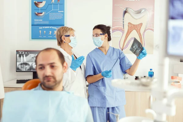 Stomatologist doctor and orthodontist assistant examining teeth radiography