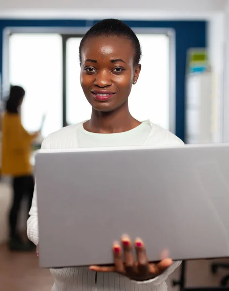 Afrikaanse videograaf glimlachend op camera vasthouden op laptop — Stockfoto