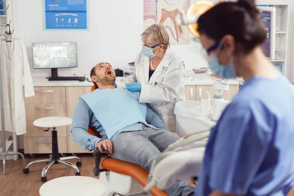 Chorego pacjenta siedzącego na krześle dentystycznym z otwartymi ustami — Zdjęcie stockowe