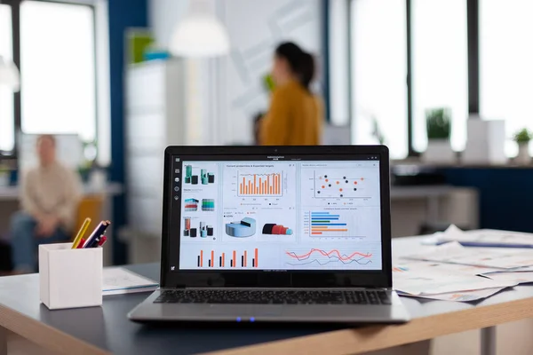 Close up of laptop in start up company office with charts and statistics — Stock Photo, Image