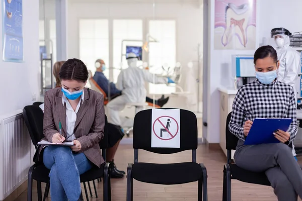 Patiënt met gezichtsbescherming masker schrijven op registratieformulier — Stockfoto