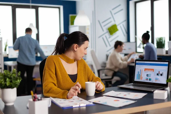 Imprenditrice seduta alla scrivania in ufficio ad analizzare grafici — Foto Stock