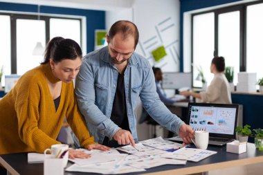 Dizüstü bilgisayarın önünde yıllık istatistikleri analiz eden çok sayıda çalışan var.