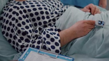 Hasta bir hastanın parmakları üzerinde tıbbi oksimetreyle yatakta dinlenmesi yakındır.