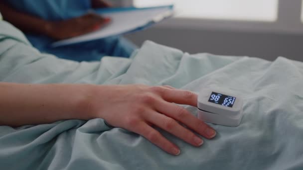 Крупный план госпитализированной женщины с датчиком частоты сердечных сокращений пальцев — стоковое видео