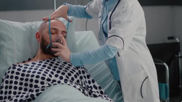 Patienten sitter i sängen medan kvinnlig läkare sätter syrgasmask — Stockvideo