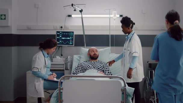 Ασθενής συζητά με γιατρούς ενώ ξεκουράζεται στο κρεβάτι κατά τη διάρκεια της ιατρικής αποκατάστασης — Αρχείο Βίντεο