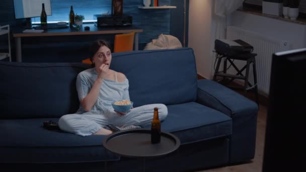 Focused young woman paying attention to horror film eating popcorn — Stock Video