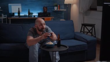 Geceleri oturma odasında video oyunu oynayan rekabetçi kararlı bir adam.