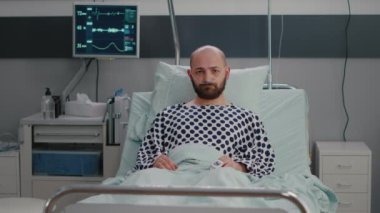 Burnunda oksijen tüpü olan üzgün hasta bir adam kameraya kötü bakıyor.