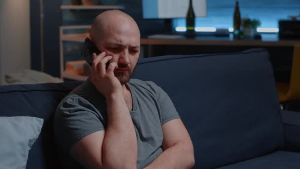 Молодой грустный шокированный мужчина с хронической болезнью, имеющий плохие новости на смартфоне — стоковое видео