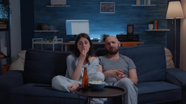 Чувствительная пара смотрит драматический фильм по телевизору плачет сидя на диване — стоковое видео