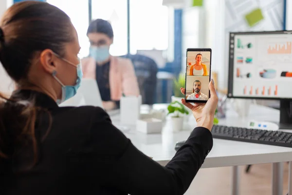 Achteraanzicht van vrouw met gezichtsmasker praten tijdens videogesprek — Stockfoto