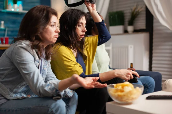 Multi ethnic friends upset after losing virtual reality gaming competition