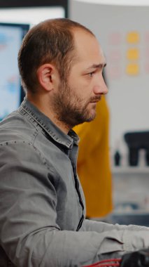 Videograf kameraya bakıp gülümsüyor ve yaratıcı bir iş yerinde çalışıyor.