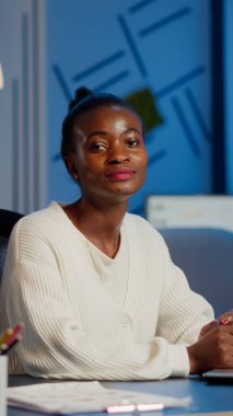 Yorgun siyah kadın yönetici kameraya bakıyor.