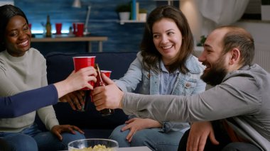 Çok ırklı arkadaşlar birlikte vakit geçirir, bira şişelerine tezahürat ederler.