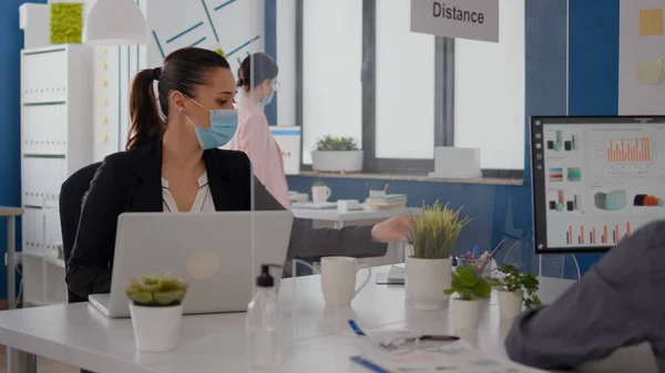 Compañeros con máscaras faciales de protección trabajando juntos en una nueva oficina normal — Foto de Stock