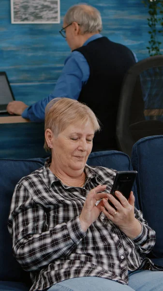Middle aged woman relaxing holding smartphone reading news — Stock Photo, Image
