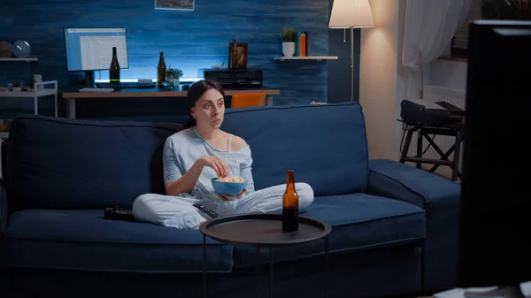 Frau isst Popcorn und schaut sich eine interessante Serie im Fernsehen an — Stockfoto