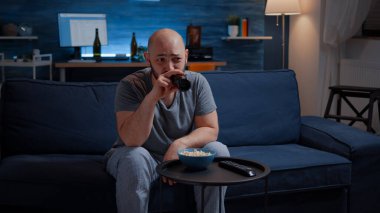 Komik adam gülerek TV 'de komedi filmi izliyor ve patlamış mısır yiyor.