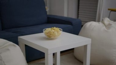 Boş parti odasındaki ahşap masaya konmuş abur cubur kızartma kasesi.