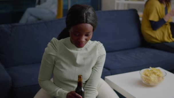 Fechar o retrato da mulher negra olhando para a câmera bebendo cerveja para o aniversário do amigo — Vídeo de Stock