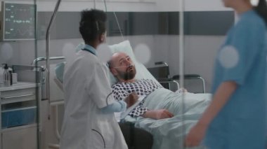 Afro-Amerikalı doktor hasta adamı kontrol ediyor. Hastalık belirtilerini izliyor.