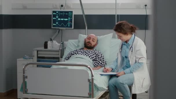 Hombre enfermo descansando en la cama con tubo de oxígeno hablando con el médico explicando el síntoma de la enfermedad — Vídeo de stock