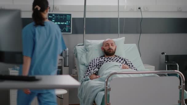 開業医のアシスタントは、病気の回復中に病気の男性に患者のベッドを手配 — ストック動画