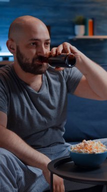 Televizyonun karşısında oturan sinirli profesyonel oyuncu, futbol maçlarını kaybediyor.