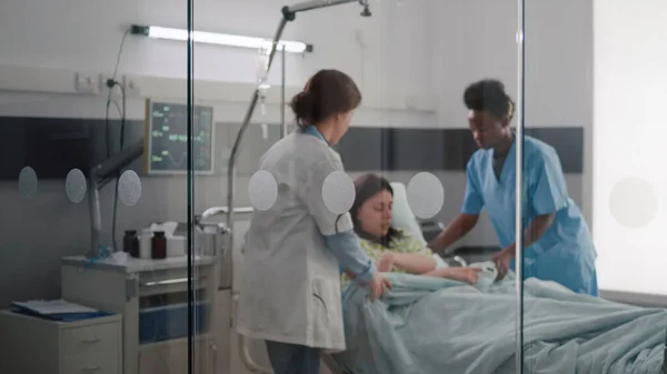 病気の緊急時に患者がベッドに入るのを助ける医療チーム — ストック写真
