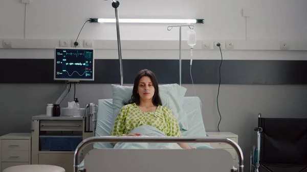 Patienten bär med näsan syrerör tittar in i kameran sitter i sängen — Stockfoto