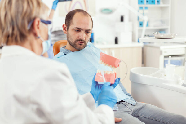 Стоматолог объясняет правильную гигиену зубов с помощью скелета во время