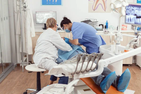 Больной человек сидит на стоматологическом стуле во время медицинского осмотра — стоковое фото