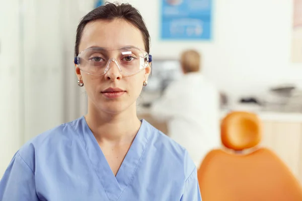 Detailní záběr ženy zdravotní sestra v uniformě při pohledu do kamery při práci v nemocnici stomatologie — Stock fotografie